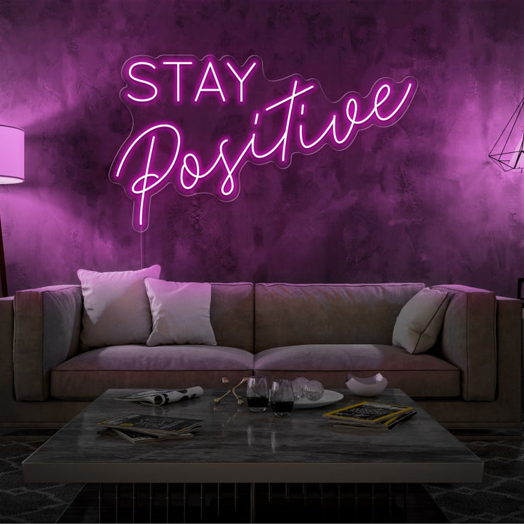 hot pink stay positive neon sign hanging on living room wall