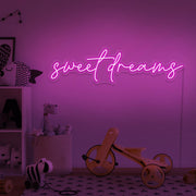 hot pink sweet dreams neon sign hanging on kids bedroom wall