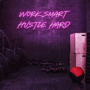 hot pink work smart hustle hard neon sign hanging on gym wall
