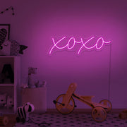 hot pink xoxo neon sign hanging on kids bedroom wall