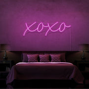 hot pink xoxo neon sign hanging on bedroom wall