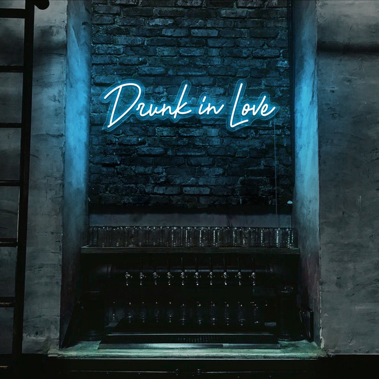 ice blue drunk in love neon sign hanging on bar wall