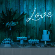 ice blue love neon sign hanging on timber wall above dessert table