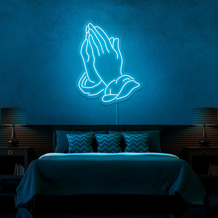ice blue praying hands neon sign hanging on bedroom wall