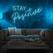 ice blue stay positive neon sign hanging on living room wall