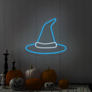 ice blue witch hat neon sign hanging on wall above pumpkins