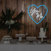 ice blue you and me neon sign hanging on timber wall above dessert table