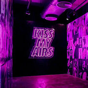 hot pink kiss my airs neon sign hanging on wall in sneaker store