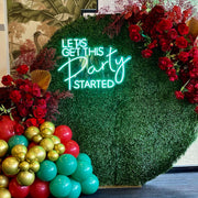 green lets get this party started neon sign hanging on garden wall backdrop frame with flowers and balloons