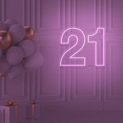 light pink 21 neon sign hanging on wall with balloons