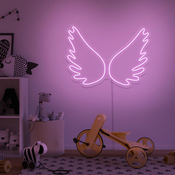 light pink angel wings neon sign hanging on kids bedroom wall