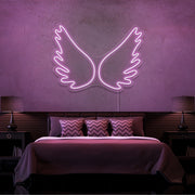 light pink angel wings neon sign hanging on bedroom wall