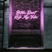 light pink bitch don't kill my vibe neon sign hanging on bar wall
