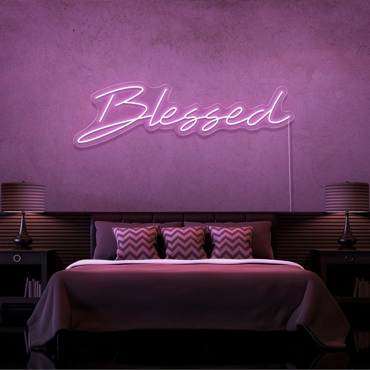 light pink blessed neon sign hanging on bedroom wall