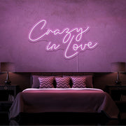 light pink crazy in love neon sign hanging on bedroom wall