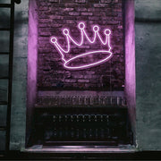 light pink crown neon sign hanging on bar wall