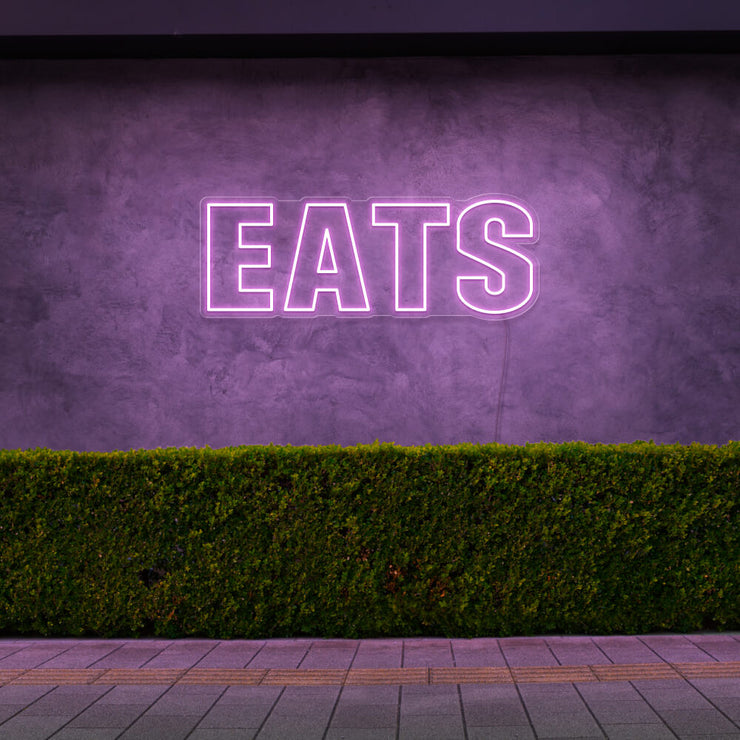 light pink eats neon sign hanging on outside wall