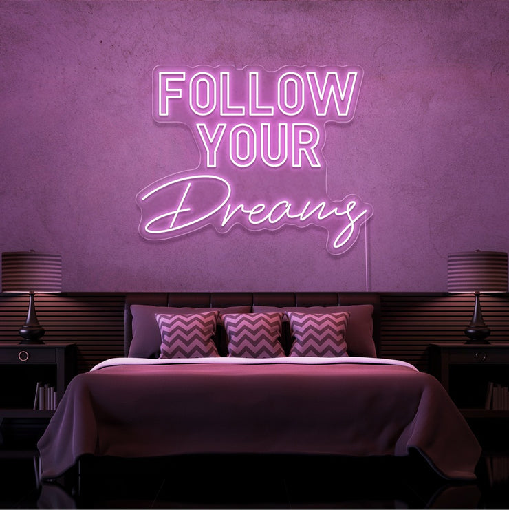 light pink follow your dreams neon sign hanging on bedroom wall