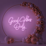 light pink good vibes only neon sign hanging inside balloon hoop backdrop