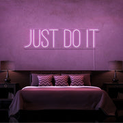 light pink just do it neon sign hanging on bedroom wall
