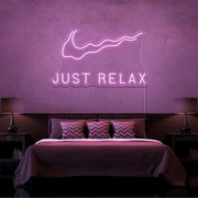 light pink just relax neon sign hanging on bedroom wall