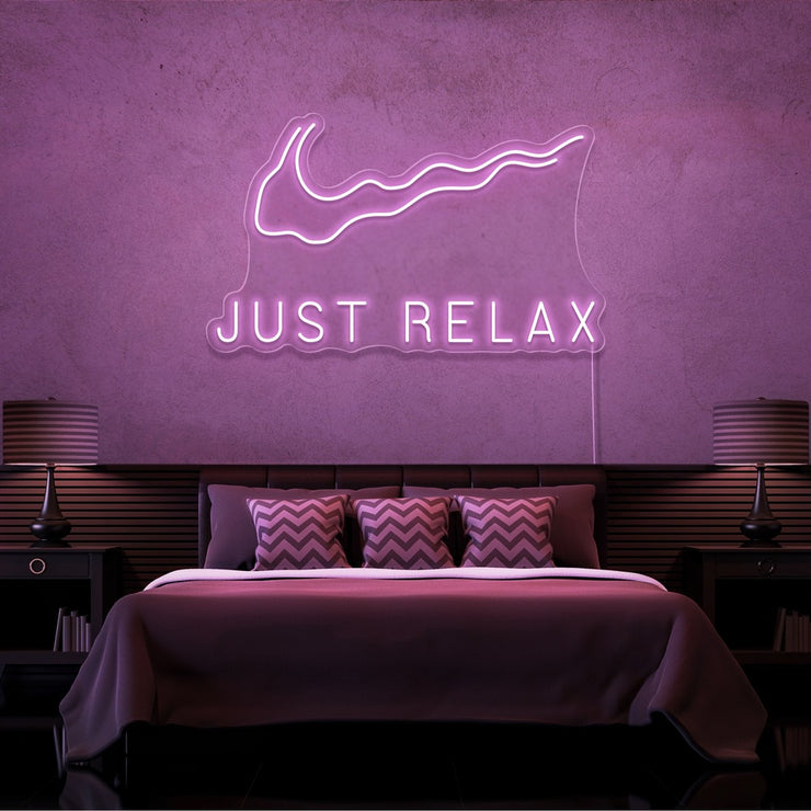 light pink just relax neon sign hanging on bedroom wall