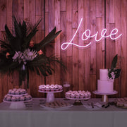 light pink love neon sign hanging on timber wall above dessert table