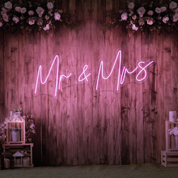 light pink mr and mrs neon sign hanging on wall with flowers