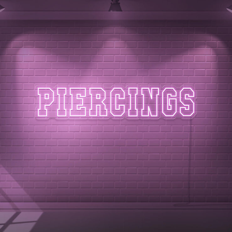 light pink piercings neon sign hanging on wall