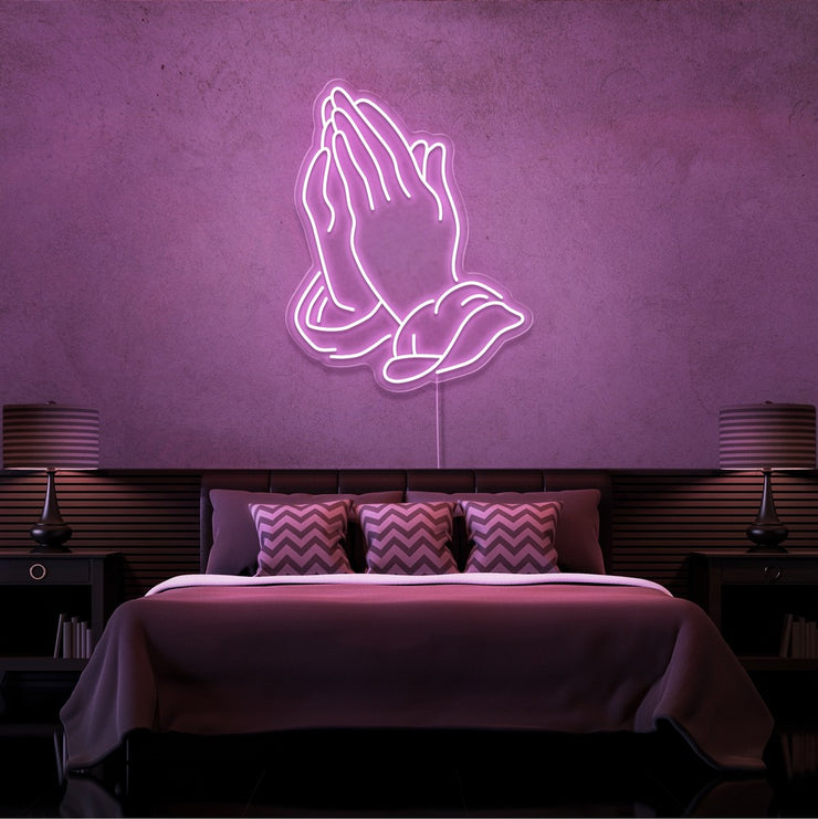 light pink praying hands neon sign hanging on bedroom wall