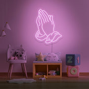 light pink praying hands neon sign hanging on kids bedroom wall