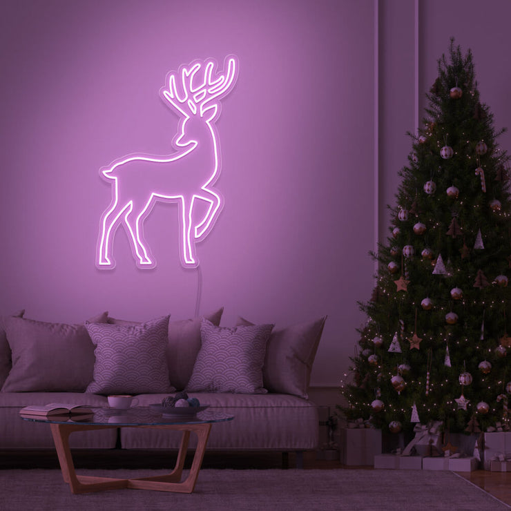 light pink reindeer neon sign hanging on living room wall next to christmas tree
