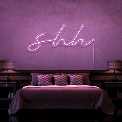 light pink shh neon sign hanging on bedroom wall