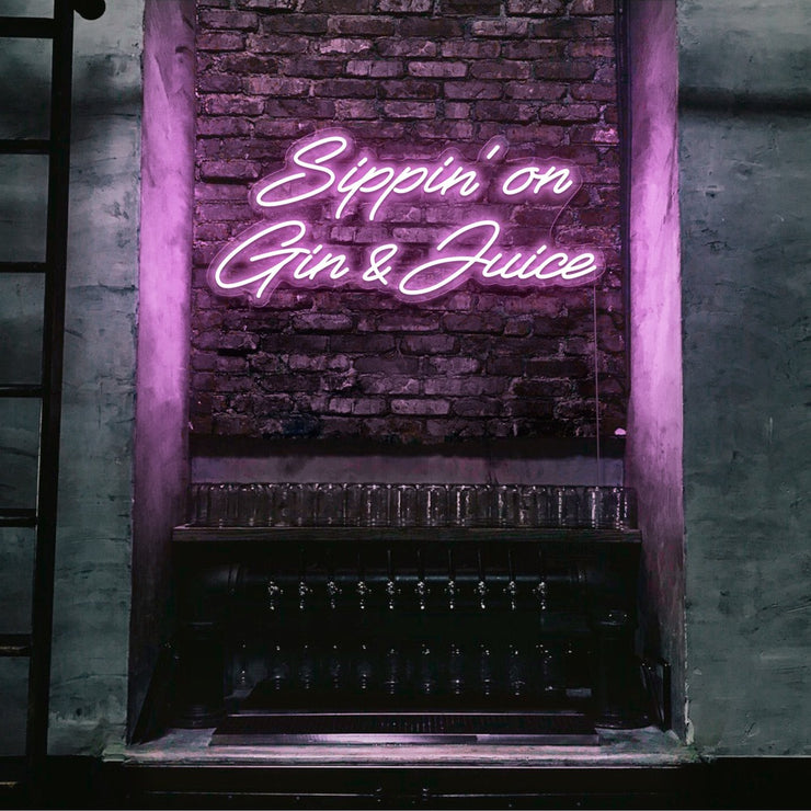 light pink sippin on gin and juice neon sign hanging on bar wall