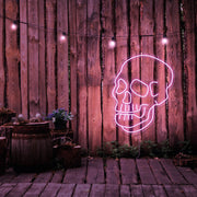 light pink skull neon sign hanging on timber fence