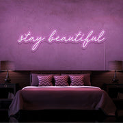 light pink stay beautiful neon sign hanging on bedroom wall
