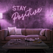 light pink stay positive neon sign hanging on living room wall