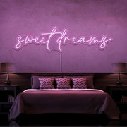 light pink sweet dreams neon sign hanging on bedroom wall