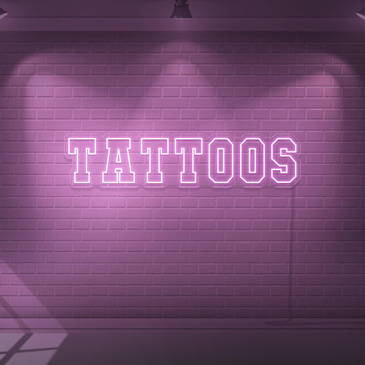 light pink tattoos neon sign hanging on wall