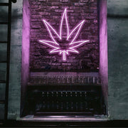 light pink weed leaf neon sign hanging on bar wall