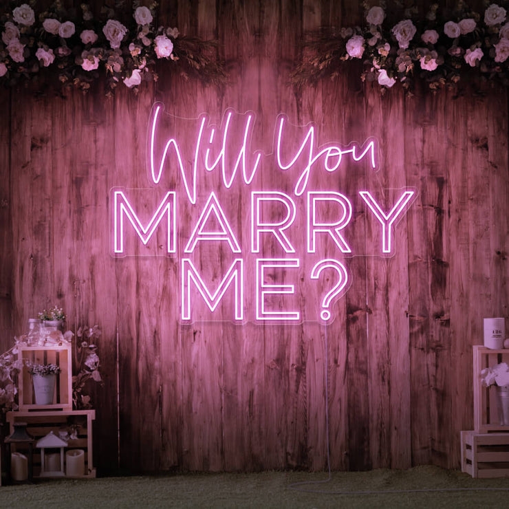 light pink will you marry me neon sign hanging on timber wall