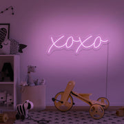 light pink xoxo neon sign hanging on kids bedroom wall