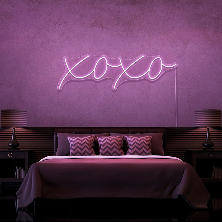 light pink xoxo neon sign hanging on bedroom wall