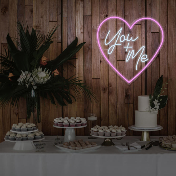 light pink you and me neon sign hanging on timber wall above dessert table