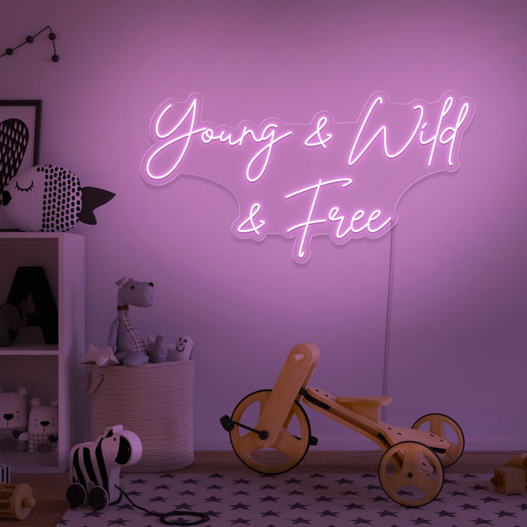 light pink young wild and free neon sign hanging on kids bedroom wall
