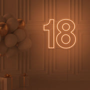 orange 18 neon sign hanging on wall with balloons