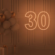 orange 30 neon sign hanging on wall with balloons