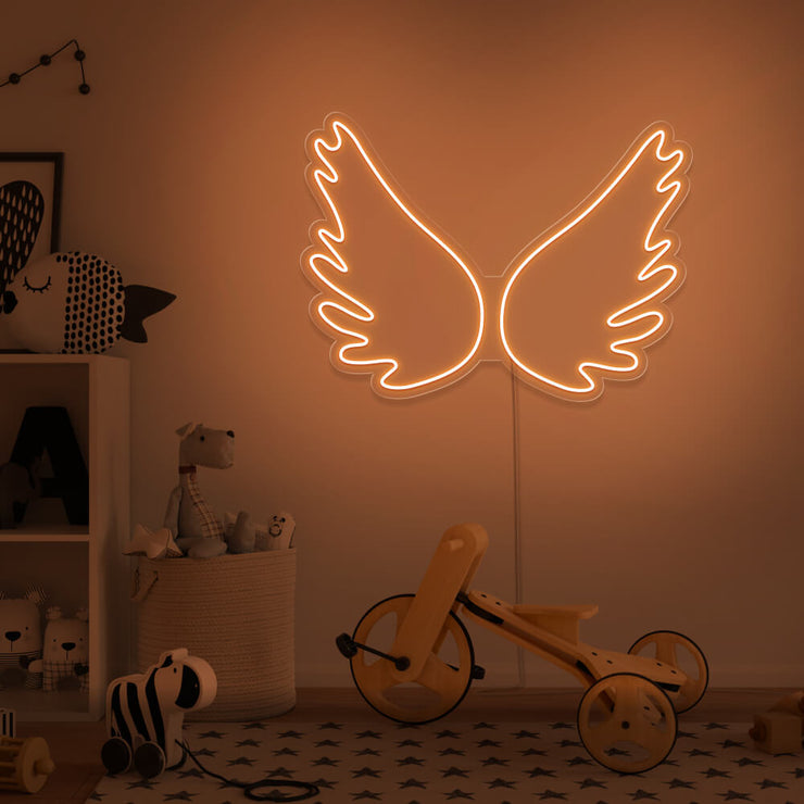 orange angel wings neon sign hanging on kids bedroom wall