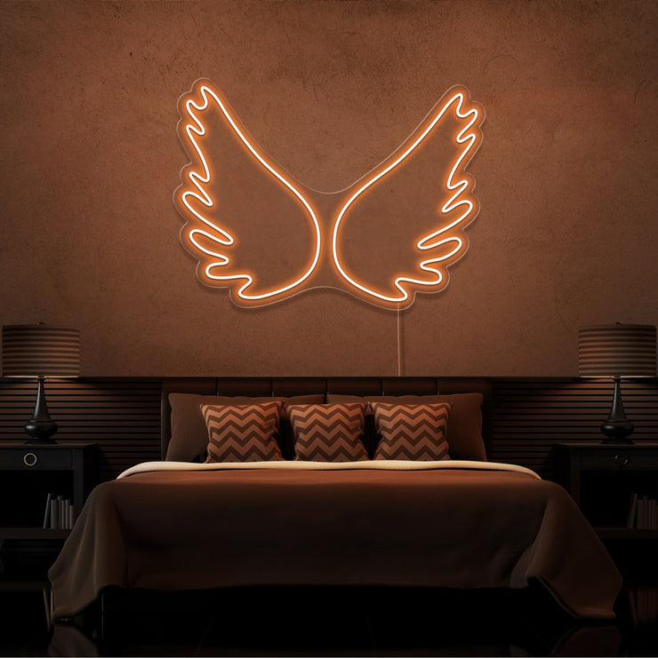 orange angel wings neon sign hanging on bedroom wall