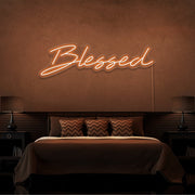 orange blessed neon sign hanging on bedroom wall